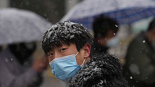 Un hombre espera para hacerse la prueba de Covid-19 mientras nieva en Pekín