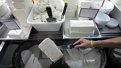 A shop assistant lifts a slab of feta cheese in Athens.