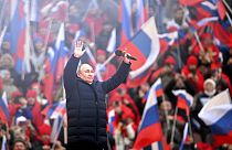 Vladimir Poutine salue la foule après son discours au stade olympique de Moscou, le 18 mars 2022