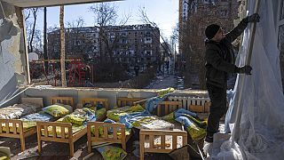Egy férfi leszedi a függönyt a bombázás miatt megrongálódott óvodában március 18-án, Kijevben