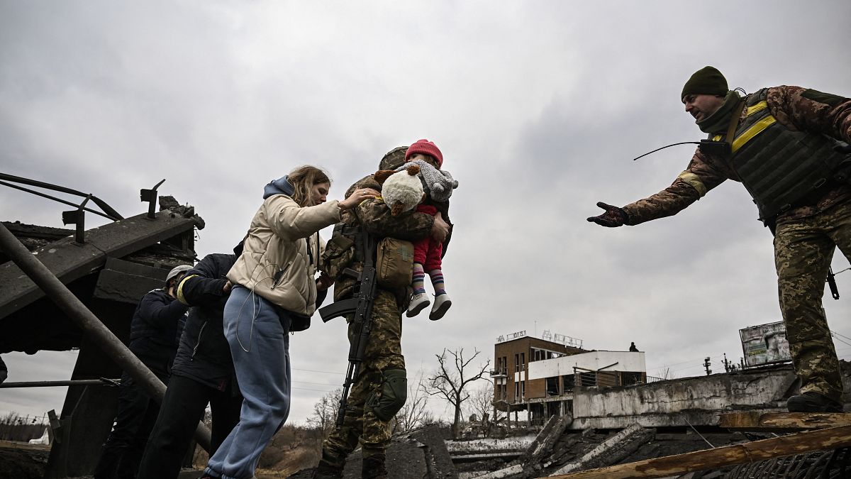 أحد عناصر فرق الطوارئ الأوكرانية يحمل طفلا.