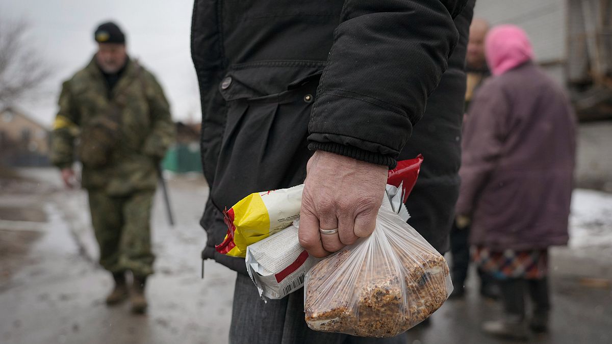 رجل يحمل منتجات غذائية خارج العاصمة كييف - أوكرانيا. 2022/03/02