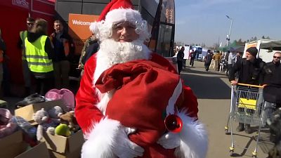 Man dressed as Santa Claus at border crossing and giving gifts to children
