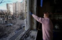 A woman measures a window before covering it with plastic sheets in a building damaged by a bombing the previous day in Kyiv, Ukraine, Monday, March 21, 2022.
