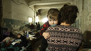 Una mujer lleva en brazos a un bebé en un refugio improvisado en Mariúpol, Ucrania