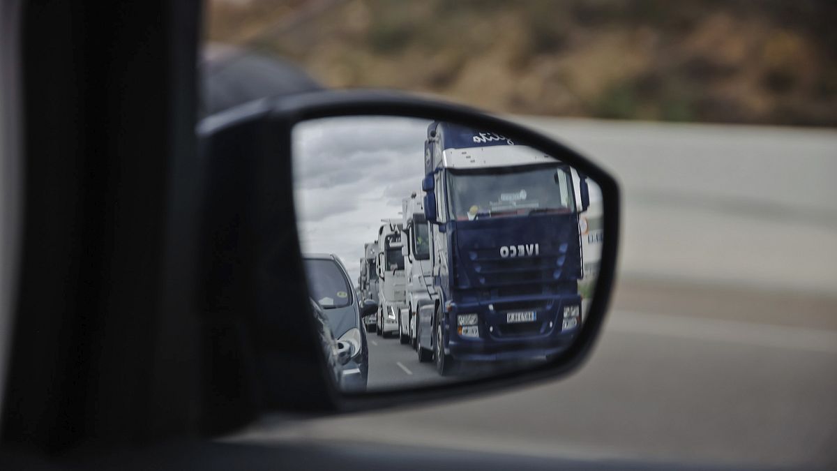 A long line of trucks driving slowly are reflected in a wing mirror of a car during a truckers strike in Torrejon de Ardoz, just outside of Madrid, Friday March 18, 2022