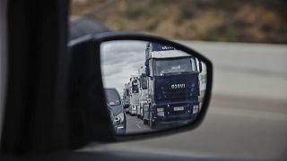 A long line of trucks driving slowly are reflected in a wing mirror of a car during a truckers strike in Torrejon de Ardoz, just outside of Madrid, Friday March 18, 2022