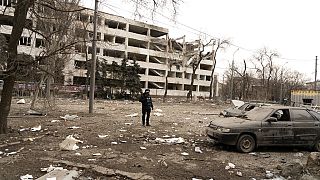 El fotógrafo de Associated Press Evgeniy Maloletka se encuentra entre los escombros de un ataque aéreo contra una universidad de Mariúpol, el jueves 10 de marzo