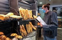 رجل يحمل قطعة خبز "باغيت" داخل مخبز بيغوت في فرساي، غرب العاصمة الفرنسية، باريس، 26 أكتوبر 2021