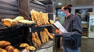 رجل يحمل قطعة خبز "باغيت" داخل مخبز بيغوت في فرساي، غرب العاصمة الفرنسية، باريس، 26 أكتوبر 2021
