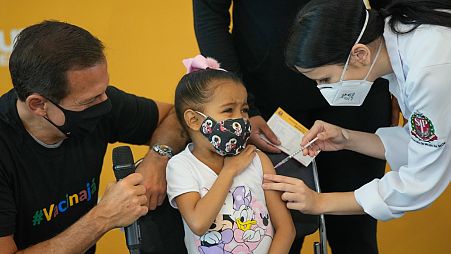 A health worker gives a shot of the Pfizer COVID-19 vaccine to 6-year-old Valentina Moreira at the Hospital da Clinicas in Sao Paulo, Brazil, Friday, Jan. 14, 2022.