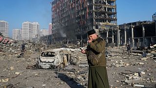 A priest prays by the ruins of a destroyed shopping center after shelling, in Kyiv, Ukraine, Monday, March 21, 2022.