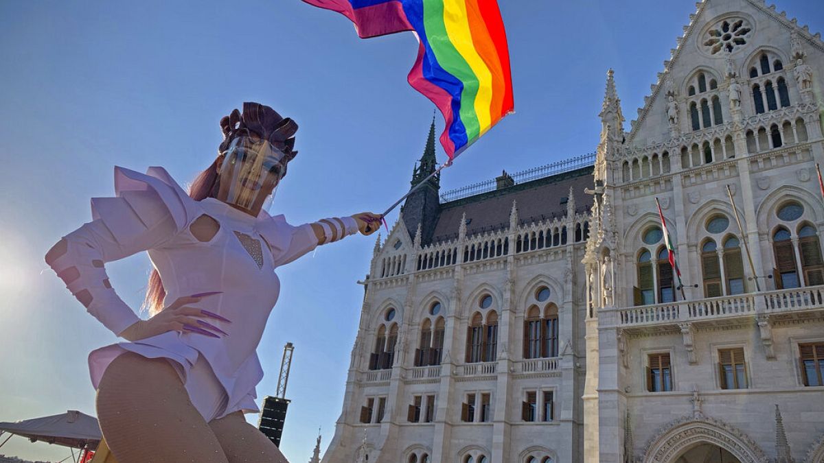 a drag queen waves a rainbow flag during an LGBT rights demonstration in front of the Hungarian Parliament, 2021. június