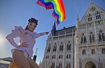 a drag queen waves a rainbow flag during an LGBT rights demonstration in front of the Hungarian Parliament, 2021. június