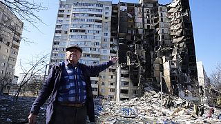 Un homme montre son appartement détruit après le bombardement d'un immeuble à Kharkiv, ce jeudi