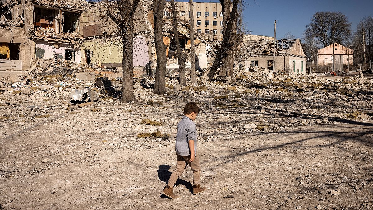 A child walks in front of a damaged school in the city of Zhytomyr, northern Ukraine. March 23, 2022