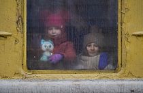 Children look out the window of an unheated Lviv bound train, in Kyiv, Ukraine, Thursday, March 3, 2022. 