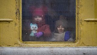 Children look out the window of an unheated Lviv bound train, in Kyiv, Ukraine, Thursday, March 3, 2022. 