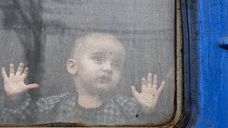 Un enfant regarde depuis un wagon de train, attendant de partir vers l'ouest de l'Ukraine à la gare de Kramatorsk, dans l'est de l'Ukraine, dimanche 27 février 2022.