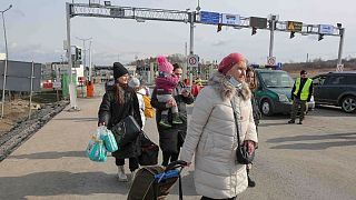زنی با فرزندش در حالی که اوکراین را ترک کرده است، تلفن همراه خود را چک می‌کند