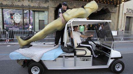 Shawn Schull hangs onto a large Oscar statue outside the Kodak Theater in Los Angeles on Friday, Feb. 20, 2009