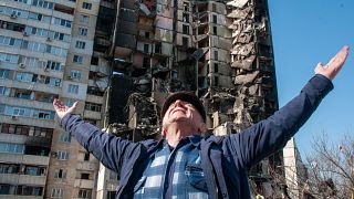 Ein Mann vor einem zerstörten Gebäude in Charkiw (Aufnahme vom 24. März 2022)
