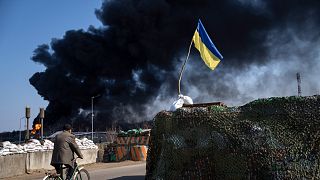 شخص يركب الدراجة بينما تتصاعد اعمدة الدخان جراء القصف الروسي على مخرن للوقود تابع للجيش الأوكراني في ضواحي كييف