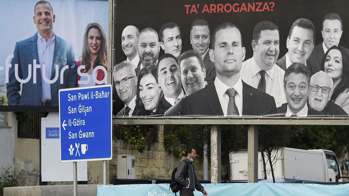 A man walks past election billboards in Msida on 24 March 2022