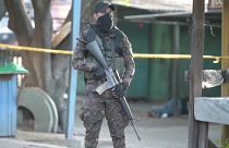 Militar salvadoreño delante del cuerpo de una víctima de la violencia pandillera