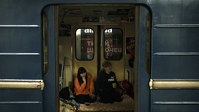 Menschen sitzen in einem Zug, der in einer U-Bahn-Station Charkiws abgestellt ist