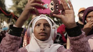 مراهقة تصور راقصات سودانيات على هاتفها المحمول في يوم اللاجئين العالمي للأمم المتحدة في القاهرة - مصر. 2019/06/20