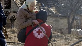 Ein Mitarbeiter des Roten Kreuzes trägt in Irpin eine Frau (Aufnahme von 11. März 22)