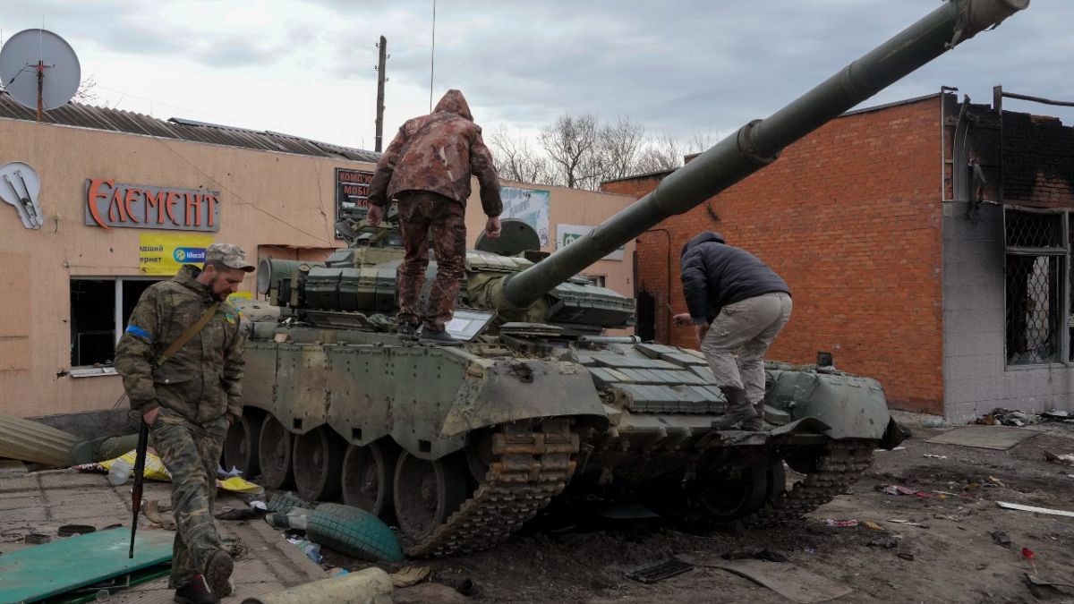 Ukrainian soldiers look at a damaged Russian tank after recent fights in the town of Trostsyanets, some 400km east of capital Kyiv, Ukraine, Monday, March 28, 2022.