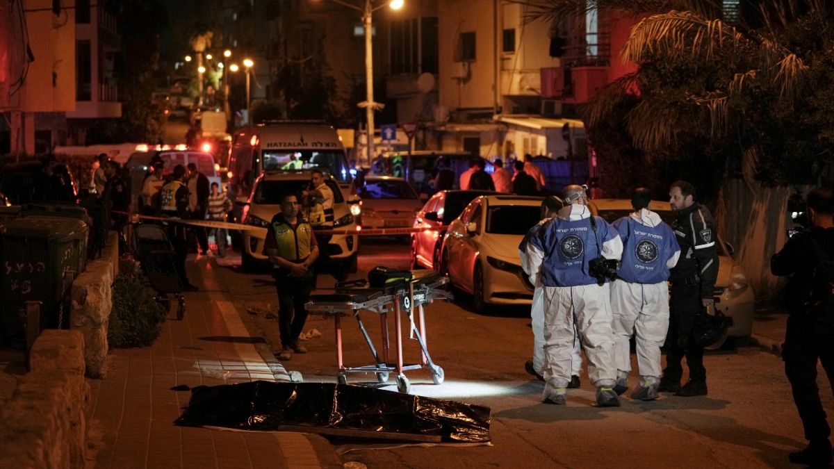 Israeli police work near the covered body of a shooting victim in Bnei Brak, near Tel Aviv, Israel, Tuesday, March 29, 2022. 