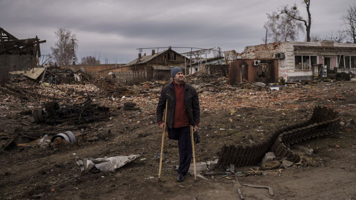 A resident stands next to parts of a destroyed Russian tank in the town of Trostsyanets, Ukraine