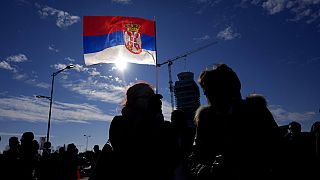 Menschen vor der serbischen Nationalflagge