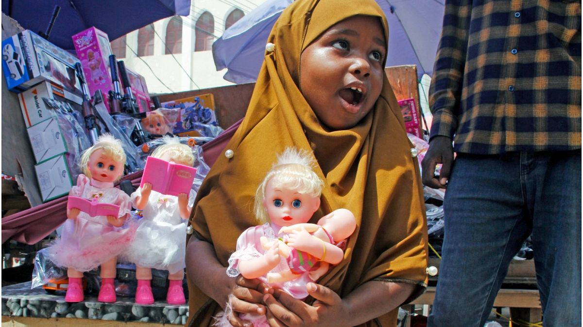 فتاة صغيرة تحمل دمية اشترتها والدتها لها بمناسبة عيد الفطر المبارك في أحد شوارع مقديشو، الصومال
