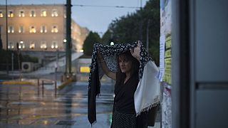 Γυναίκα προσπαθεί να προφυλαχθεί από την ξαφνική νεροποντή στην πλατεία Συντάγματος (φώτο αρχείου)