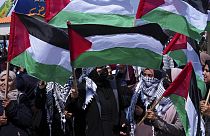 نساء فلسطينيات يلوحن بأعلامهن الوطنية خلال مسيرة لإحياء الذكرى 46 ليوم الأرض، في ميناء الصيادين في مدينة غزة، الأربعاء 30 مارس 2022