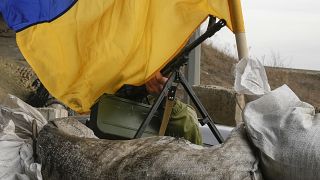 A machine gun emerges from under the Ukrainian flag on a front line position near Kharkiv, Ukraine, Saturday, March 26, 2022.