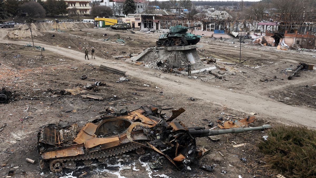 Des habitants passent devant des chars russes endommagés et un monument pour la Seconde Guerre Mondiale dans la ville de Trostyanets à l'est de Kyiv, le 28 mars 2022
