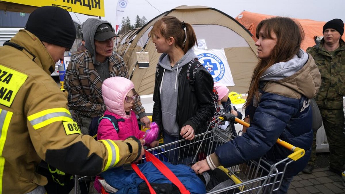 A Polish firefighter helping Ukrainian refugees, carries their belongings at border crossing in Medyka.