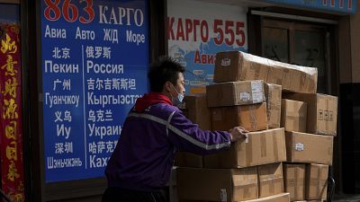 A courier worker moves goods past a shipping company for the countries including Russia and Ukraine, at a trading center also known as Russia Market in Beijing.