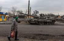 Idős nő egy megsemmisült orosz páncélozott harci jármű roncsa előtt Trosztyanecben