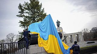 Αστυνομικοί αφαιρούν την ουκρανική σημαία με την οποία άγνωστοι κάλυψαν τανκς στο σοβιετικό μνημείο του Βερολίνου