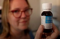 Image shows Isabelle Nodin holding a bottle of CBD oil. Her children are taking part in a large-scale medical cannabis trial in France.