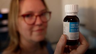 Image shows Isabelle Nodin holding a bottle of CBD oil. Her children are taking part in a large-scale medical cannabis trial in France.