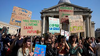 Demonstrators hold posters in front of Le Pantheon monument during a climate protest Friday, March 25, 2022 in Paris.