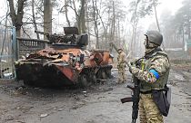 Des soldats ukrainiens examinent un véhicule militaire détruit à Irpin, près de Kyiv, en Ukraine, vendredi 1er avril 2022.