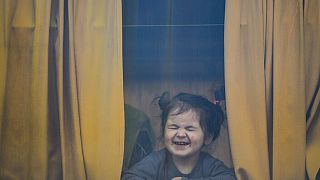 Rusya'nın saldırısı sonrası Ukrayna'dan Romanya'ya kaçan mülteci bir ailenin çocuğu otobüsün camından poz veriyor